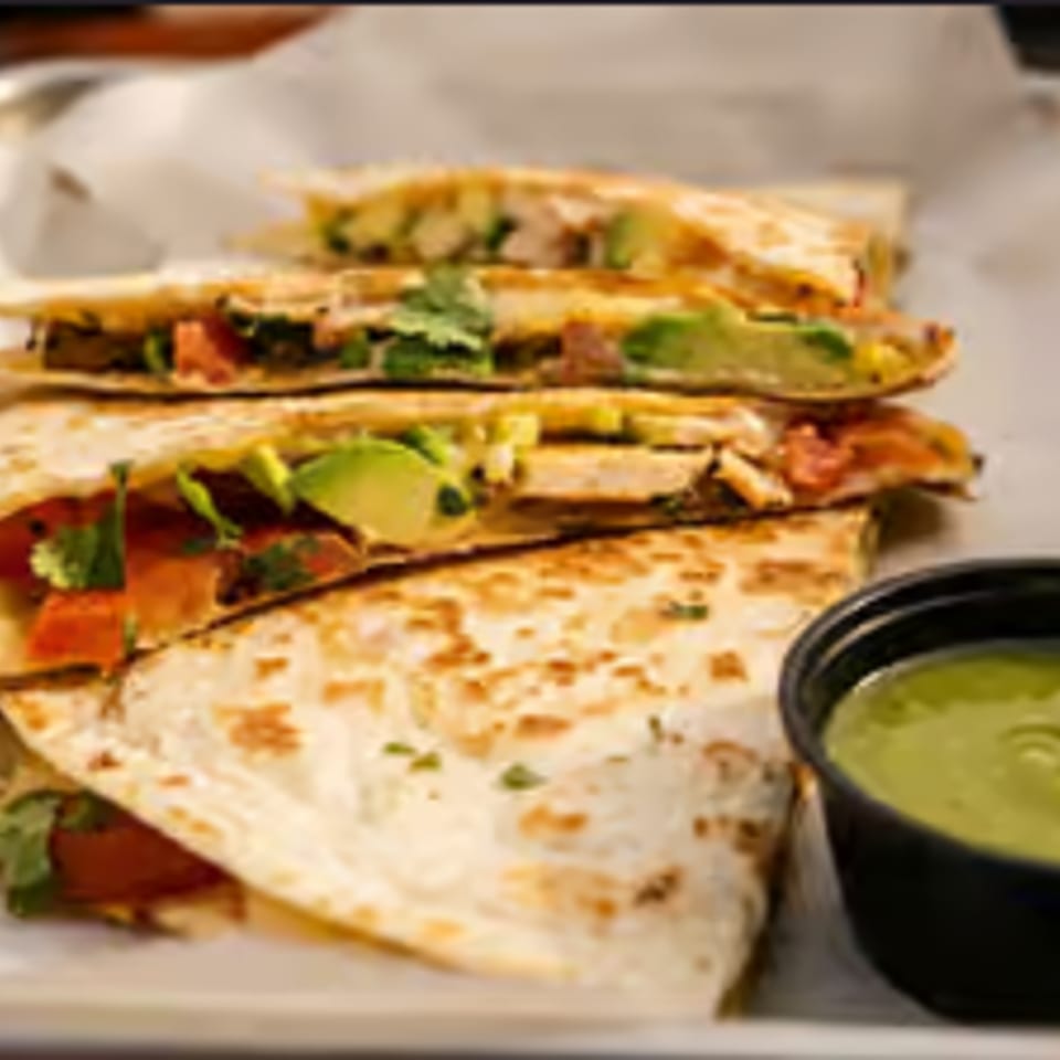 Chicken and avocado quesadillas with pico de gallo and a side of green sauce.