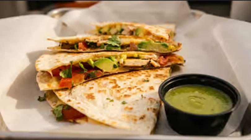 Chicken and avocado quesadillas with pico de gallo and a side of green sauce.